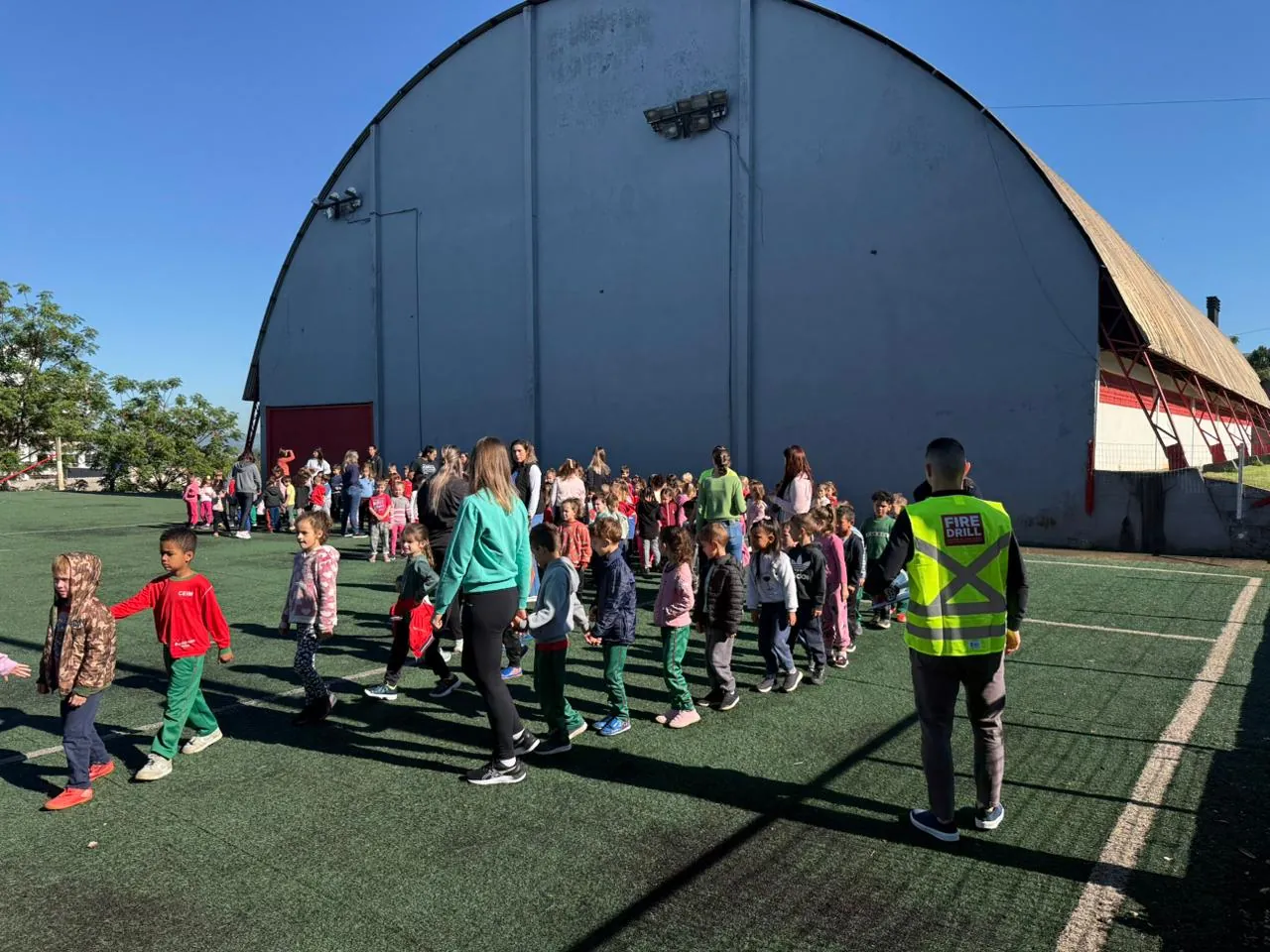 Equipe FireDrill conduzindo alunos durante simulado em pátio escolar